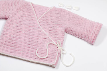 Rosa gehäkelte Baby-Wickeljacke mit weißer Einfassung und Bindeband