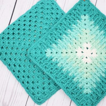 Two square crocheted teal potholders: one solid, one ombre with a hanging loop