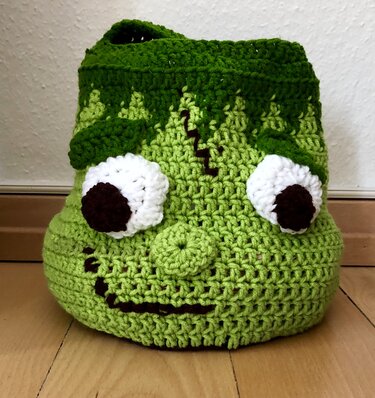 Gehäkelte grüne Henkeltasche im Frankenstein-Stil auf Holzfußboden