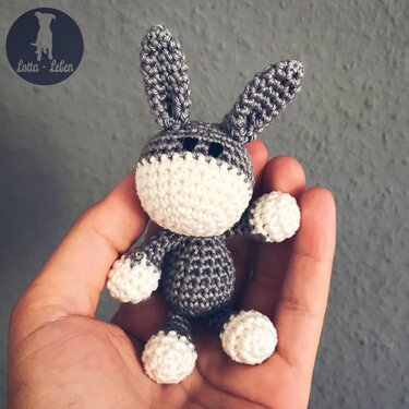 Small grey and white crocheted donkey amigurumi held in a hand.