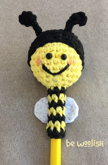 Gehäkelter schwarz-gelb gestreifter Bienen-Topper auf gelbem Bleistift mit weißen Flügeln