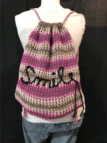 Häkelrucksack mit Streifen in Pink, Grau und Beige und schwarzem Smile-Schriftzug, Rückansicht