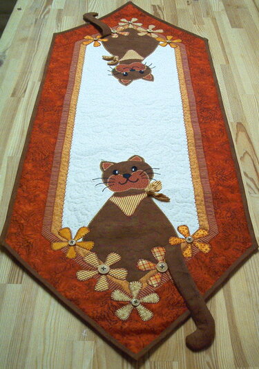 Orange-brauner gequilteter Tischläufer mit applizierten Katzenköpfen und Stoffblumen