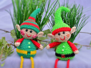 Zwei gehäkelte Weihnachtselfen in Rot und Grün mit Zipfelmützen, Spitzohren und langen Schlenkerbeinen
