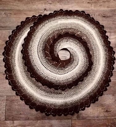 Rundes gehäkeltes Tuch in Braun und Weiß mit Spiralmuster auf Holzboden