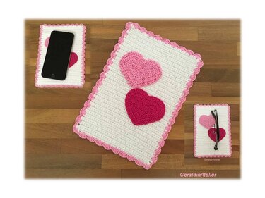 Drei rechteckige gehäkelte Untersetzer in Weiß mit rosa Muschelkante und Herzapplikationen auf Holzoberfläche.