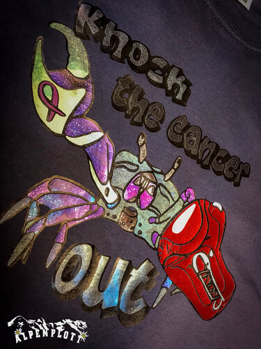 Glitzernde Krabbe mit rotem Boxhandschuh, rosa Schleife und dem englischen Schriftzug "Knock the cancer out" auf dunklem Stoff.