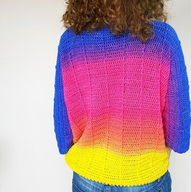 Rückenansicht eines gehäkelten Damenpullovers mit blau‑rosa‑orange‑gelbem Farbverlauf und sichtbarer Rippenstruktur