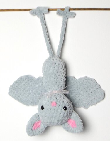Niedliche, hellgraue Amigurumi‑Fledermaus mit rosa Details, kopfüber hängend