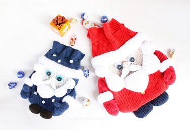 Two crocheted Santa-shaped bags, red and blue, displayed with foil-wrapped chocolates and a small gift on a white background.