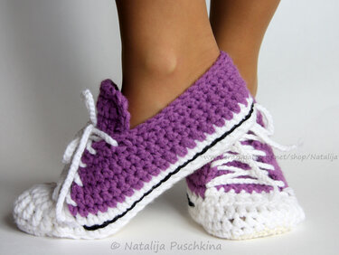 Close-up of feet wearing purple and white crocheted sneaker-style slippers with white laces.