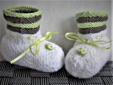 weiße gestrickte Babyschuhe mit grün-grau gestreiftem Bündchen und hellgrünem Satinband
