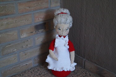 Gehäkelte Weihnachtsfrau in rotem Kleid, weißer Schürze und Brille