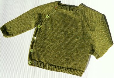 Olivgrüne, gestrickte Babyjacke mit Raglanärmeln, langen Ärmeln und schräger seitlicher Knopfleiste auf hellem, gestreiftem Untergrund.