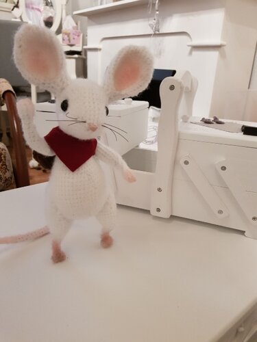 Weiße gehäkelte Amigurumi‑Maus mit rosa Ohren und rotem Halstuch auf hellem Untergrund