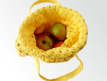Gelbe gehäkelte Tasche von oben mit Äpfeln im Inneren