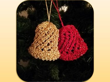Zwei gehäkelte Weihnachtsglocken in Gold und Rot an einem Tannenzweig.