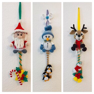 Drei gehäkelte Weihnachtsanhänger an der Wand: Weihnachtsmann, Schneemann mit Pinguinen, Rentier.