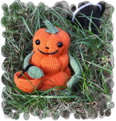 Gehäkelter Amigurumi-Kürbis in Orange und Grün im Gras