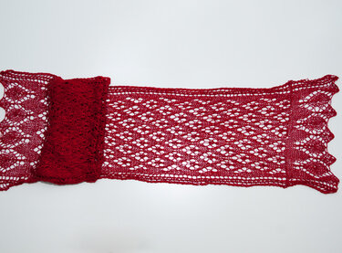 Rotes Lacetuch mit filigranem Lochmuster auf hellem Hintergrund