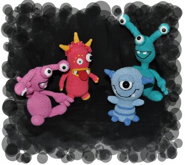 Vier gehäkelte Amigurumi-Monster: pink, rot, hellblau, türkis auf dunklem Grund.