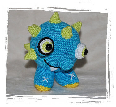 Blaues gehäkeltes Amigurumi‑Monster mit hellgrünen Stacheln und zwei Augen