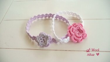 Zwei gehäkelte Stirnbänder in Lila und Weiß mit Blumenverzierungen auf hellem Hintergrund