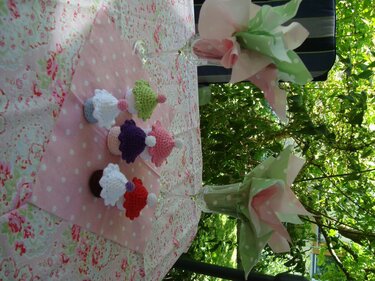Gehäkelte bunte Muffins auf rosafarbenem, gepunktetem Tuch