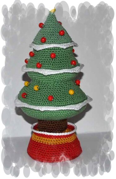 Gehäkelter grüner Tannenbaum mit weißen Borten und roten sowie gelben Perlen in rot-gelbem Topf