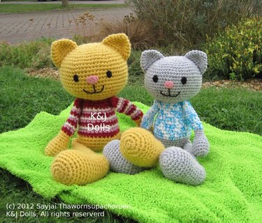 Zwei gehäkelte Katzen-Amigurumis (gelb und grau) auf grünem Tuch