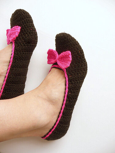 Gehäkelte dunkelbraune Ballerina-Hausschuhe mit pinker Umrandung und Schleife an den Füßen