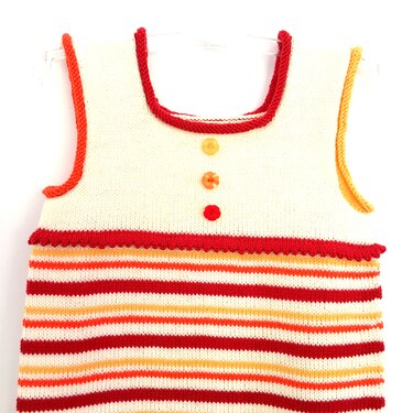 Ärmelloses gestricktes Kinderkleid creme mit roten, orangen und gelben Streifen und drei Knöpfen vorne