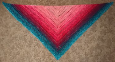Gehäkeltes Dreieckstuch in Rosa, Pink und Türkis auf hellem Boden