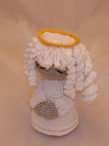 Weißes gehäkeltes Amigurumi-Engelchen mit gelbem Heiligenschein, spiralförmigen Locken und gefalteten Händen