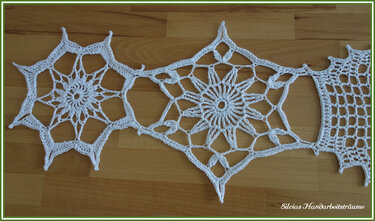 Detailansicht verbundener gehäkelter Motive mit Netzrand auf Holz