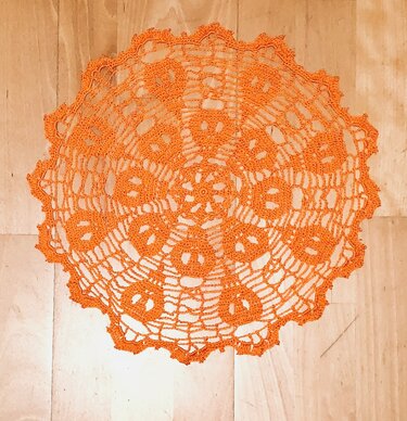 Rundes orangefarbenes gehäkeltes Deckchen mit Kürbissen