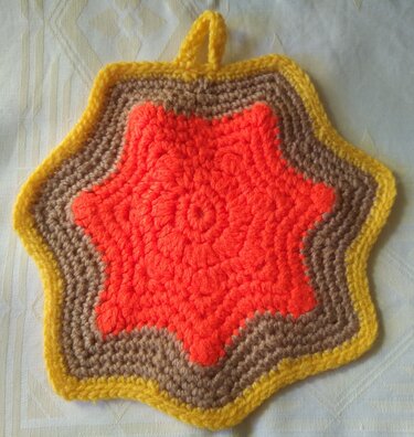 Gehäkelter sternförmiger Topflappen in Orange, Braun und Gelb mit Aufhängeschlaufe