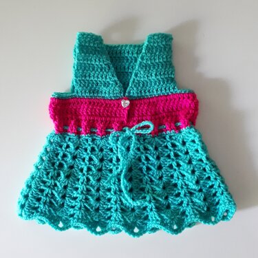 Gehäkeltes Babykleid in Türkis und Pink mit V-Ausschnitt, Herzknopf und Muschelmuster am Rock