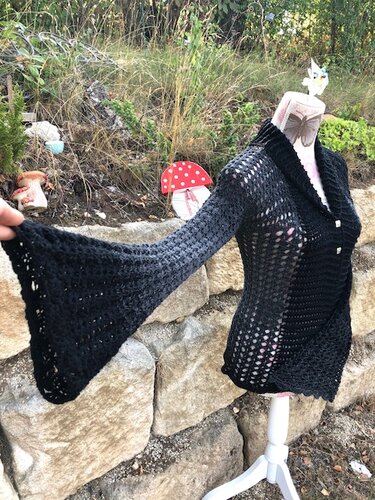 Schwarze gehäkelte Damenjacke auf Schneiderpuppe mit Ajourmuster, Schalkragen und Glockenärmeln