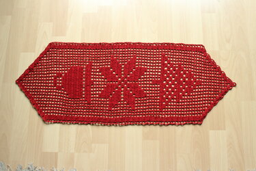 Roter gehäkelter Tischläufer mit LOVE‑Schriftzug und Schneeflocke auf hellem Holzboden