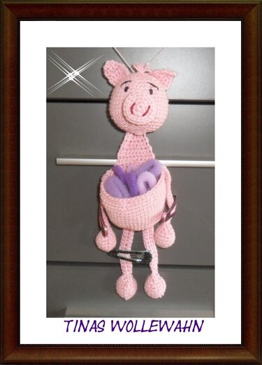 Rosa gehäkeltes Schwein-Utensilo mit lila Haargummis und einer schwarzen Haarspange