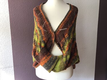 Gestrickter Seelenwärmer in Braun, Orange und Grün mit Loch‑Blattmuster und breitem Rippenbund auf einer Schneiderpuppe