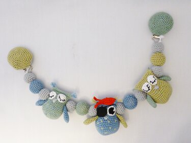 Gehäkelte Kinderwagenkette mit drei Eulen, bunten Kugeln und Befestigungsclips in Pastellfarben.