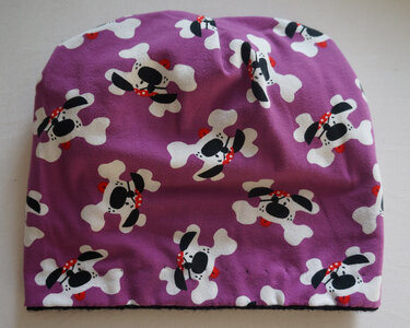 Lila Beanie mit weißem Knochenmuster und stilisierten Hunden mit roten Halstüchern