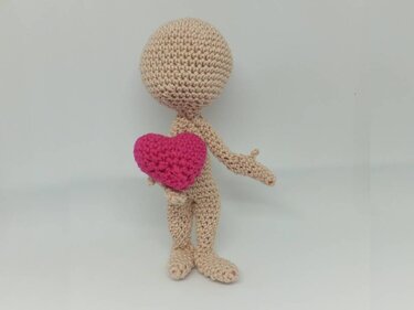 Beige gehäkelte Amigurumi-Puppe hält rosa Herz