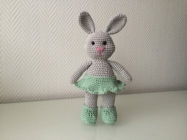 Grau gehäkeltes Amigurumi-Häschen mit mintgrünem Rock und passenden Schuhen