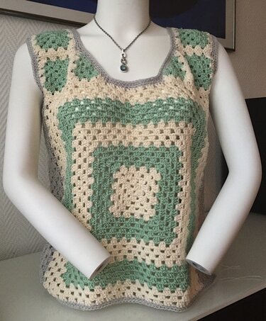 Schaufensterpuppe trägt gehäkeltes Damen-Top aus großen Granny-Squares in Creme, Pastellgrün und grauem Rand
