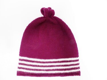 Beerfarbene, glatt rechts gestrickte Mütze mit weißen Streifen am Saum und kleiner Schlaufe oben