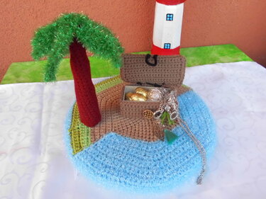 Gehäkelte Miniatur-Insel mit Palme, Leuchtturm und offener Schatzkiste mit Schmuck