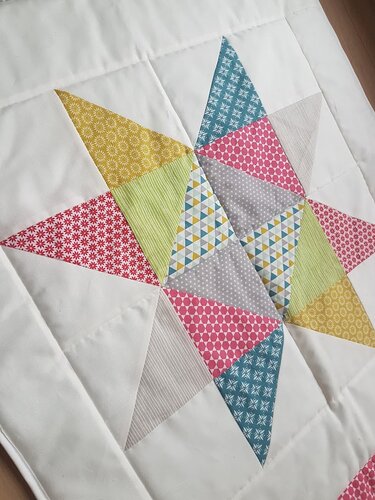 Quilt mit sternförmigem Patchwork aus bunten Stoffmustern auf weißem Hintergrund